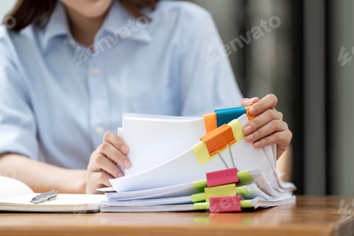 Preview: Businesswoman hands working in Stacks of paper files for searching and checking unfinished document