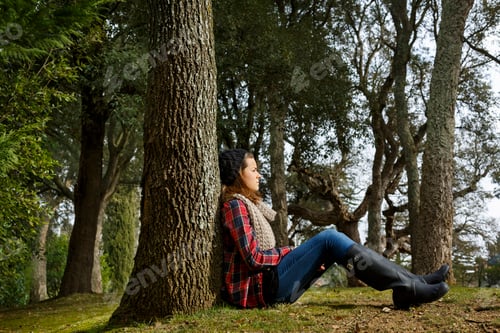 Preview: Teenage girl sitting against tree in forest