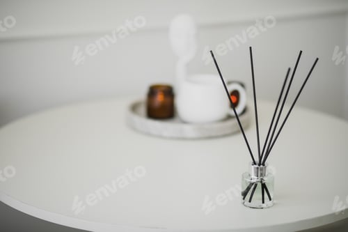 Preview: Still life with white mug, aromatic sticks and candles on a table in a cozy living room.