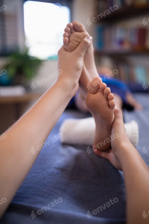 Preview: Close-up of boy receiving foot massage from young female therapist