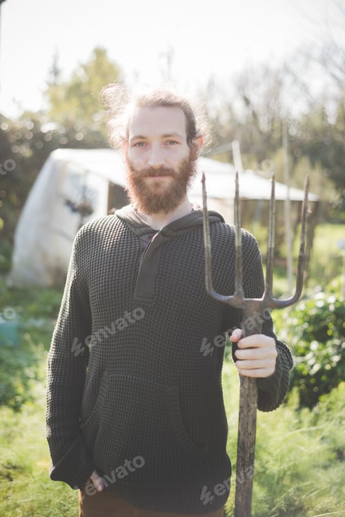 Preview: Young man in garden holding fork