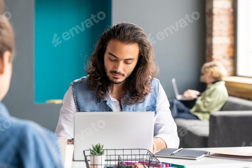 Preview: Contemporary mixed-race businessman or office manager sitting in front of laptop