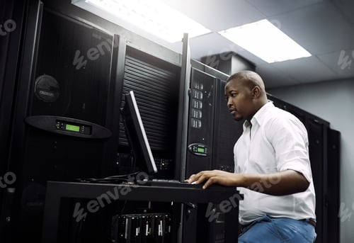 Preview: Cropped shot of an IT technician using a computer while working in the server room of a data center