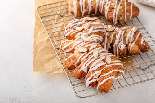 Preview: Bear claw pastry on a cooling rack with glaze and almonds