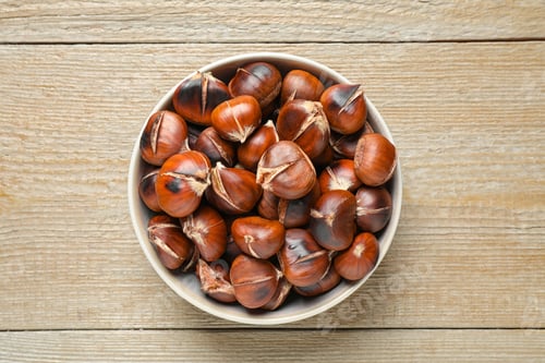 Preview: Delicious roasted edible chestnuts on wooden table, top view