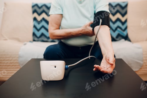 Preview: Senior woman taking measures blood pressure at home. Self care of elderly health.