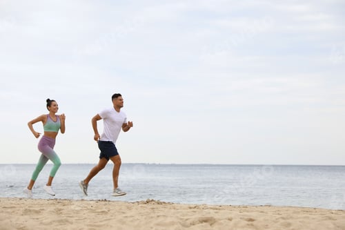 Preview: Couple running together on beach, space for text. Body training