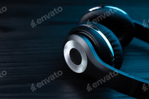 Preview: Black headphone on dark wooden background. Stylish wireless headset in neon light.
