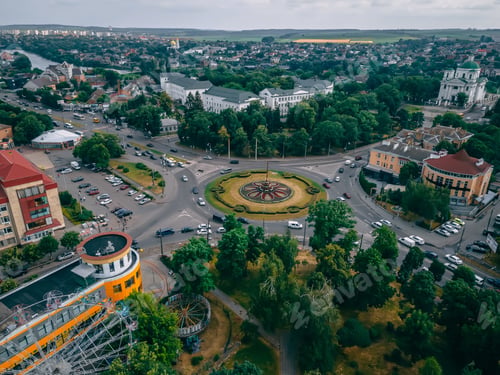 Preview: Aerial view of roundabout road with circular cars in small european city at summer afternoon
