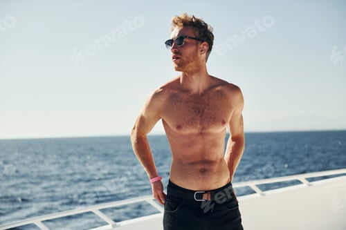 Preview: In sunglasses. Young male tourist is on the yacht on the sea. Conception of vacation