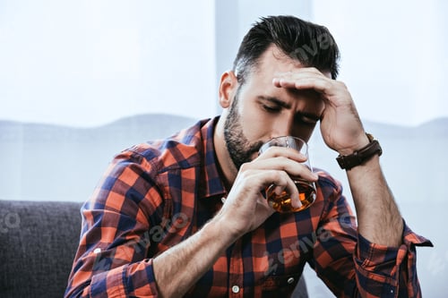 Preview: close-up portrait of depressed young man drinking whiskey