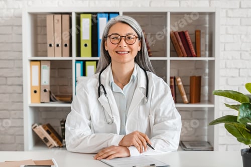 Preview: Happy middle-aged woman doctor sitting at the desk