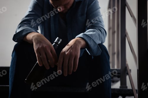 Preview: Addicted man with alcoholic drink on stairs indoors, closeup