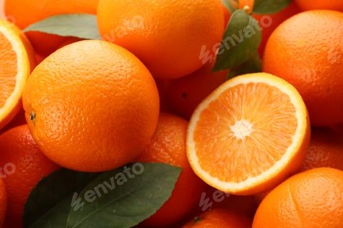Preview: Cut and whole fresh ripe oranges with green leaves as background, closeup