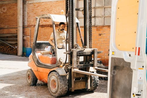 Preview: Man Operating Forklift at Industrial Warehouse During Sunny Afternoon