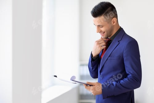 Preview: Happy businessman reading contract in the office