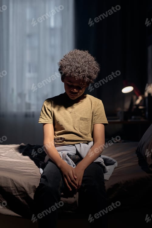 Preview: Teenage Boy Sitting on Bed in Dramatic Light