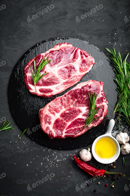 Preview: Cooking on kitchen table fresh raw pork marbled steaks on black background, top view