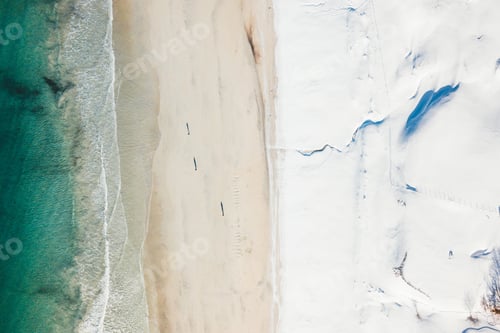 Preview: Overhead shot of a beach where the sand meets the snow from the mountains