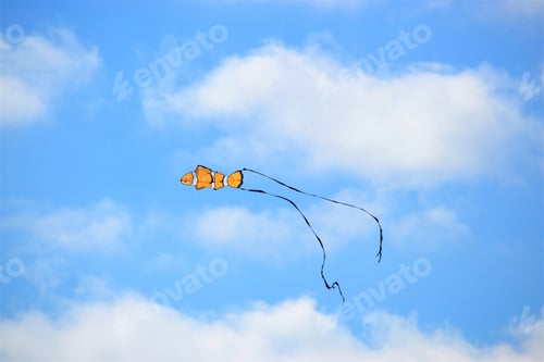 Preview: Colorful blue sky with white fluffy clouds and pops of color fish kite