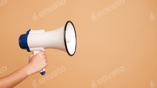 Preview: Unrecognizable person holding megaphone in brown studio