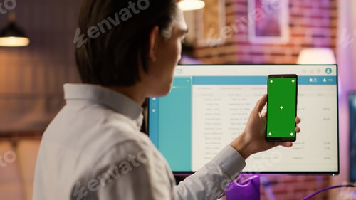 Preview: Male freelancer holding smartphone with greenscreen on display