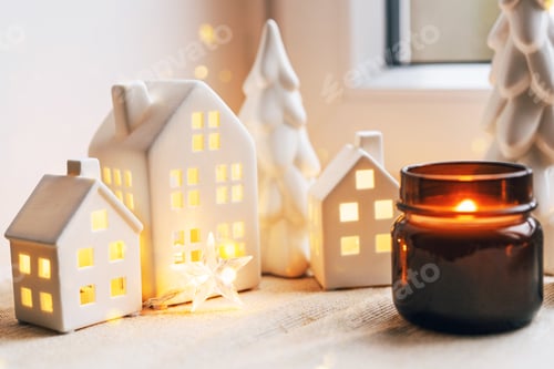 Visualização: Cena de Natal aconchegante com casas de cerâmica e luz de velas perto de uma janela