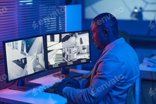 Preview: Black man looking at surveillance camera footage in security center office