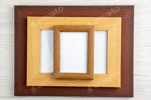 Preview: Top view of stacked small medium and big empty picture frames on white wooden background