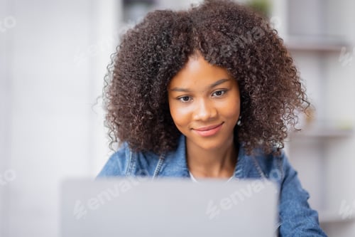 Preview: Creative young african american woman working and talking on laptop in her studio
