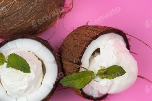 Preview: Vanilla ice cream balls in fresh coconut halves decorated with mint leaves on a pink background