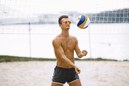 Preview: Young naked man with volleyball ball at beach