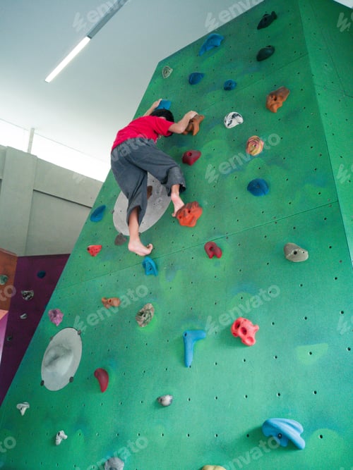 Preview: low angle of a boy rock climbing