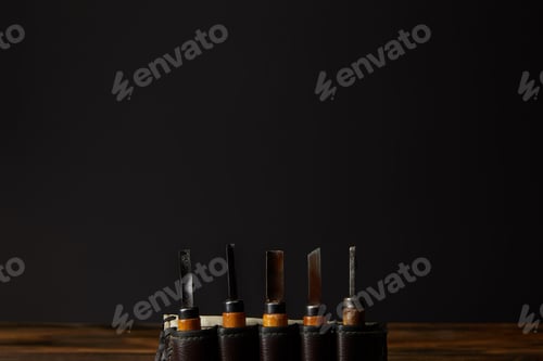 Preview: chisels in leather case at table on black background