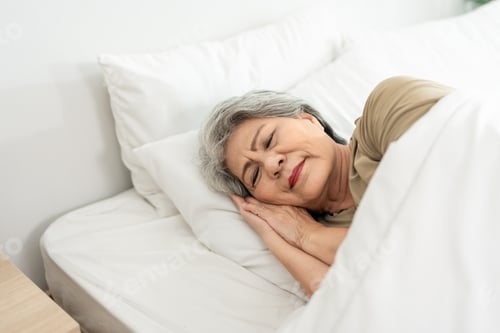 Preview: Asian senior woman lying down on bed in bedroom in morning at home.