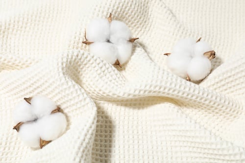 Preview: Clean waffle towel and cotton flowers as background, top view