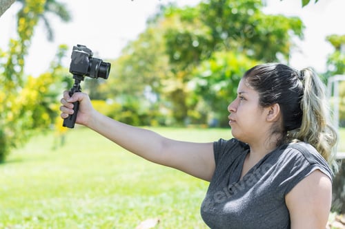 Preview: influencer girl raising her hand holding the camera while recording a vlog video for her networks.