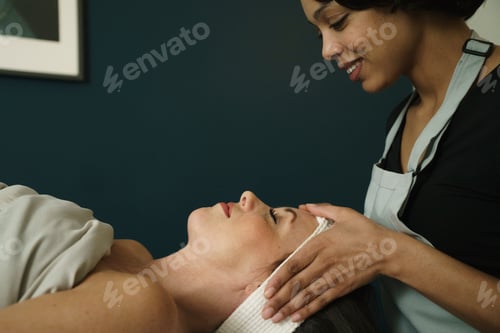 Preview: Therapist giving woman head massage at health and beauty clinic.