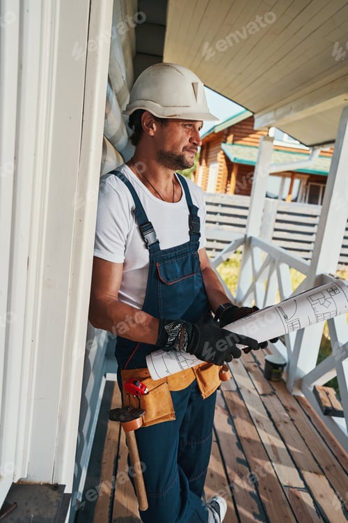 Preview: Male builder with tool belt holding roll of paper