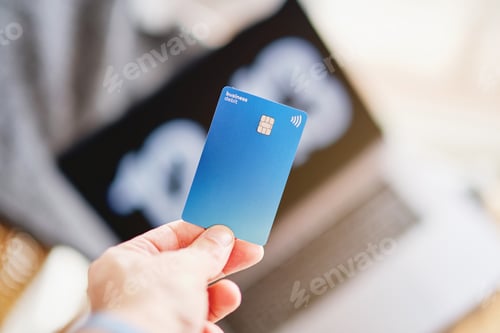 Preview: Woman holding a blue credit card with her hand in front of the computer about to pay for a purchase