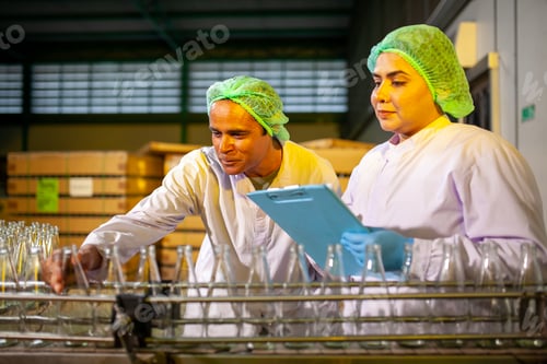 Preview: Asian workers is checking product bottles of fruit juice in the beverage factory.