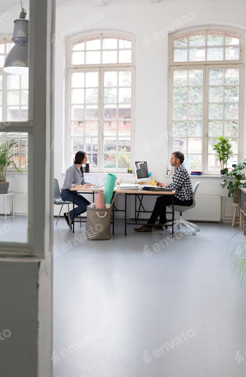 Preview: Colleagues working at desk in a loft office