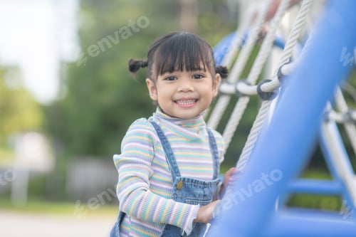Preview: Cute children. Asian girl climbing in a rope playground structure at the adventure park