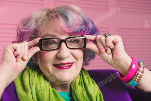 Preview: Pretty senior woman holding and wearing glasses. Concept of bright informal aged designer