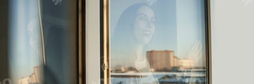 Preview: Caucasian young adult female looking through window with city reflection