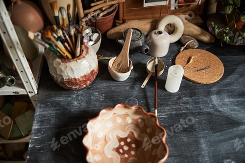 Preview: Clay bowl and paint brushes on table in pottery workshop