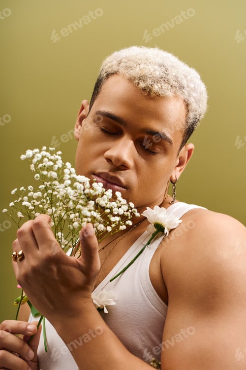 Preview: Captivating young man with dyed hair enjoys flowers in studio setting