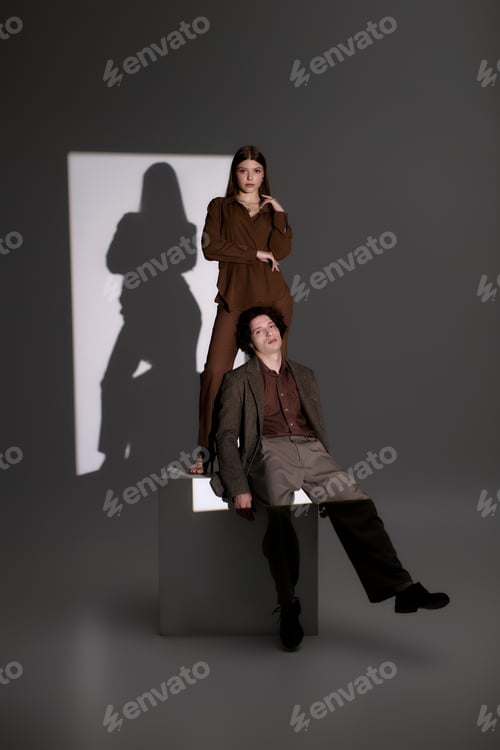 Preview: Stylish young couple exuding confidence in fashionable outfits in a grey studio