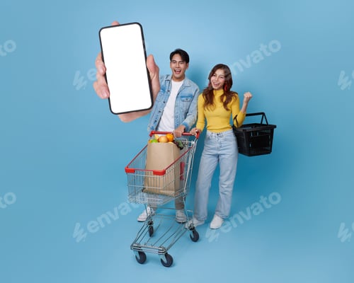 Preview: Asian couple shopping at supermarket with cart groceries holding blank smartphone