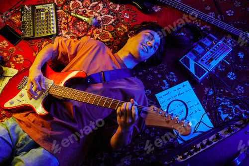 Preview: Young Guitarist Lying on Carpet in Neon